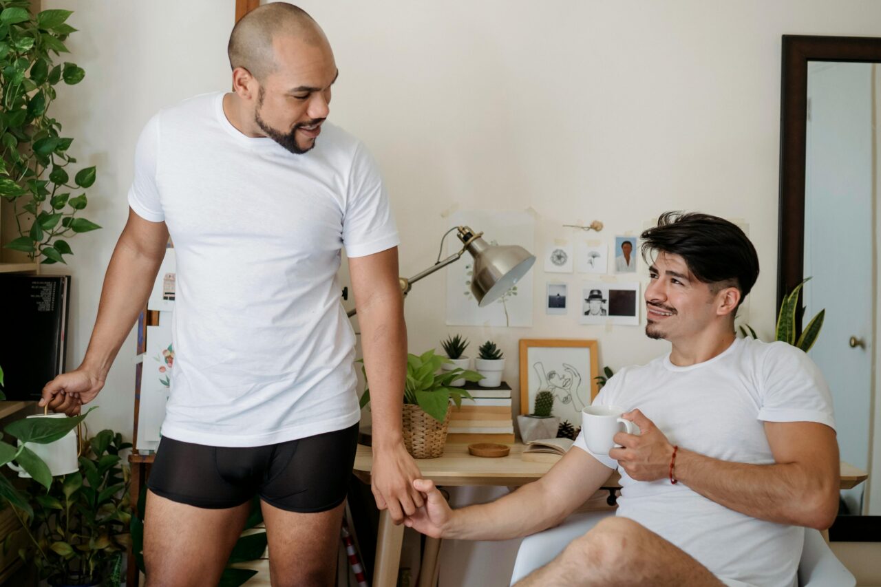 A loving gay couple enjoying a cozy moment together indoors, showcasing affection and happiness.