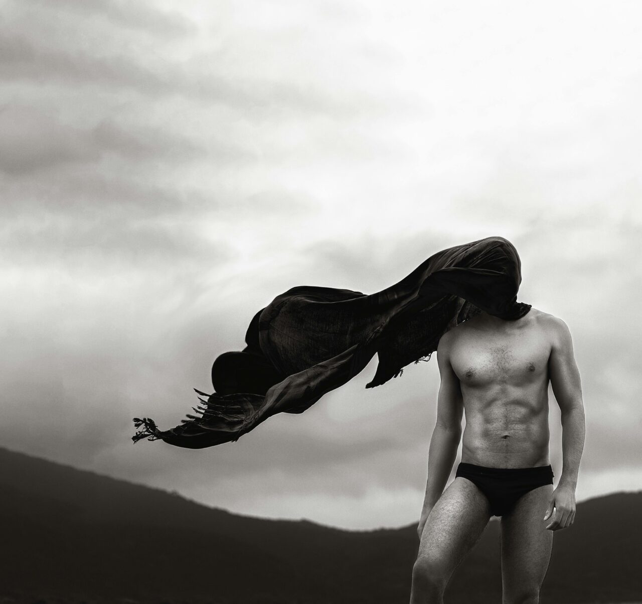 An abstract black and white portrait of a shirtless man with a flowing scarf.